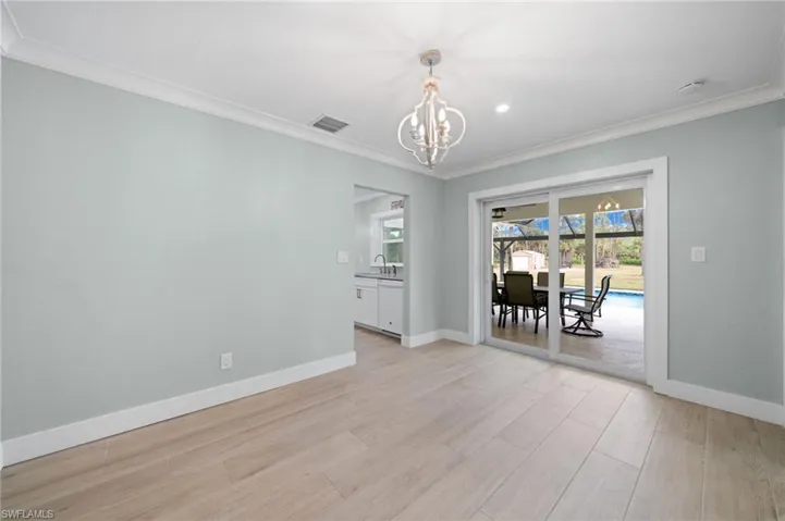 Empty room featuring light hardwood / wood-style floors, crown molding, a notable chandelier