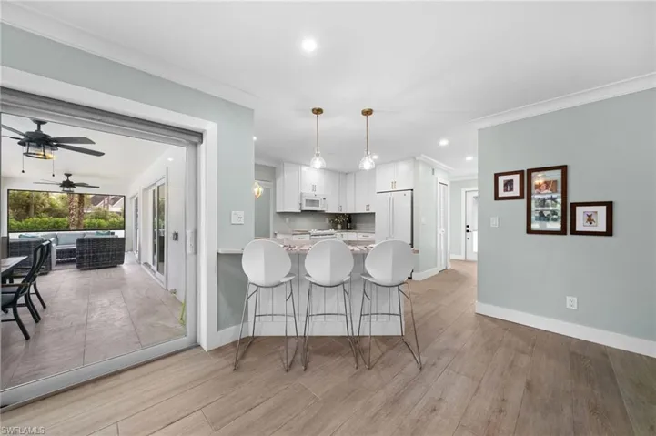 Kitchen with white appliances, white cabinets, decorative light fixtures, light hardwood / wood-style floors, and kitchen peninsula