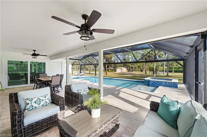 View of pool with outdoor lounge area, a patio, an in ground hot tub, and a lanai