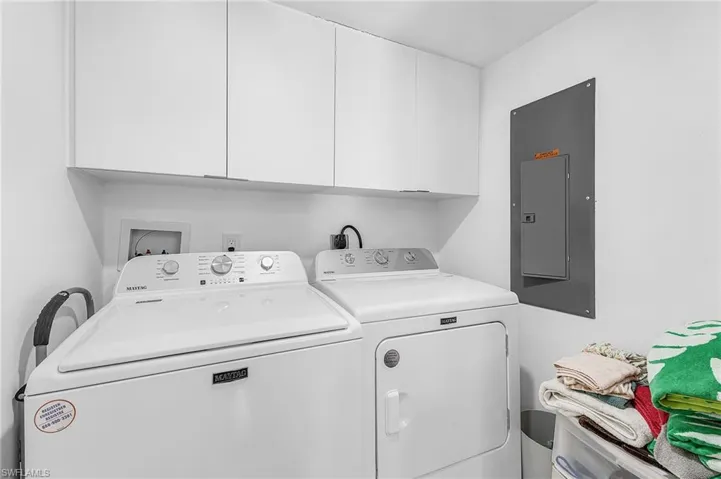 Laundry room with electric panel, separate washer and dryer, and cabinet space