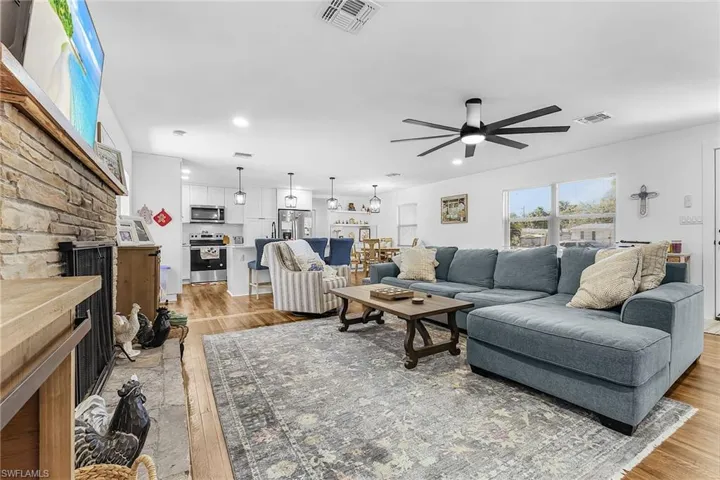 Living area featuring light wood-style flooring, a ceiling fan, a stone fireplace, and recessed lighting