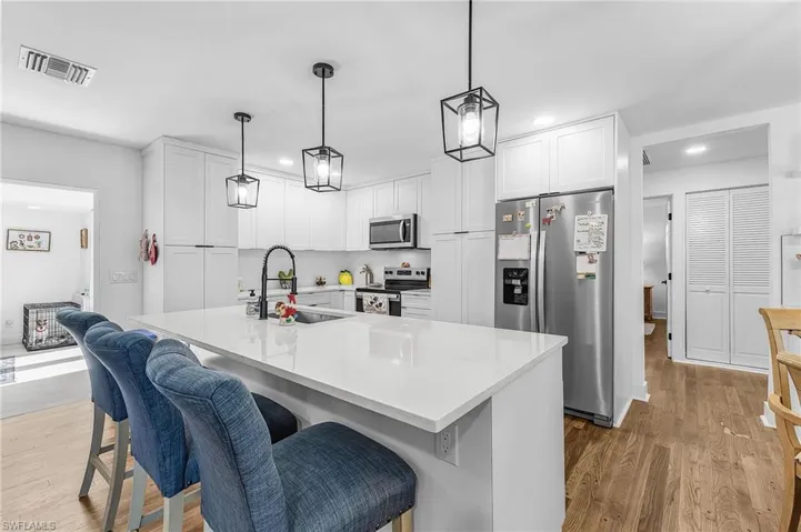 Kitchen featuring appliances with stainless steel finishes, a breakfast bar area, white cabinets, a center island with sink, and recessed lighting