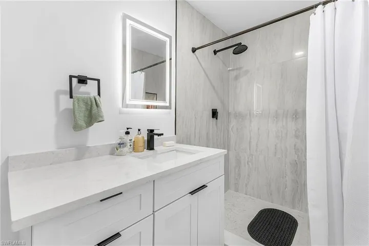 Full bath featuring tiled shower and vanity