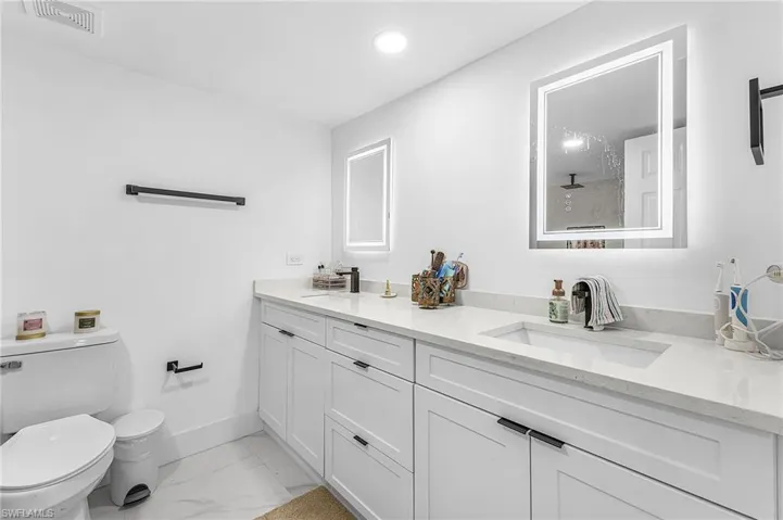 Bathroom with double vanity, light marble finish floors, and recessed lighting