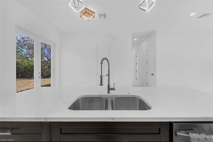 Kitchen featuring light stone countertops and dishwasher