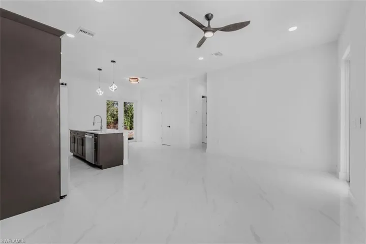Unfurnished living room with a ceiling fan, recessed lighting, and light marble finish floors