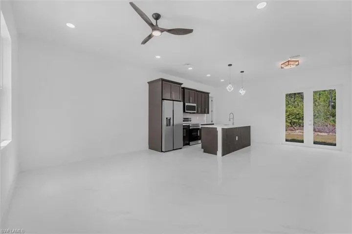 Kitchen featuring dark wood finish cabinets, ceiling fan, stainless steel appliances, and open floor plan