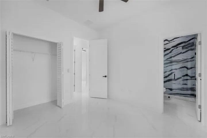 Unfurnished bedroom featuring ensuite bath, a ceiling fan, and a closet