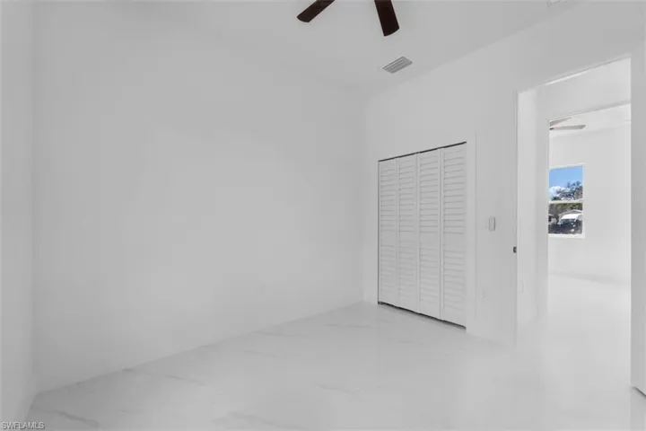 Unfurnished bedroom with a closet, a ceiling fan, and light marble finish flooring