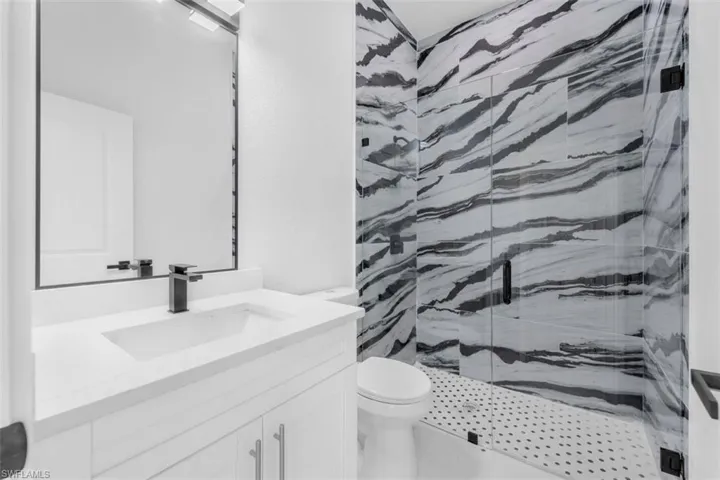 Full bathroom featuring a marble finish shower and vanity