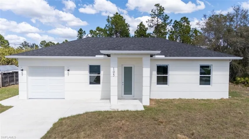 View of front of house with a front lawn, a shingled roof, driveway, and an attached garage