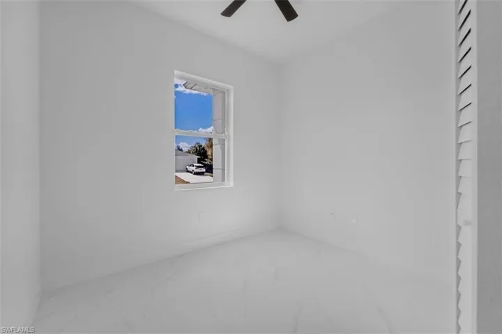 Spare room featuring marble look tile flooring and ceiling fan