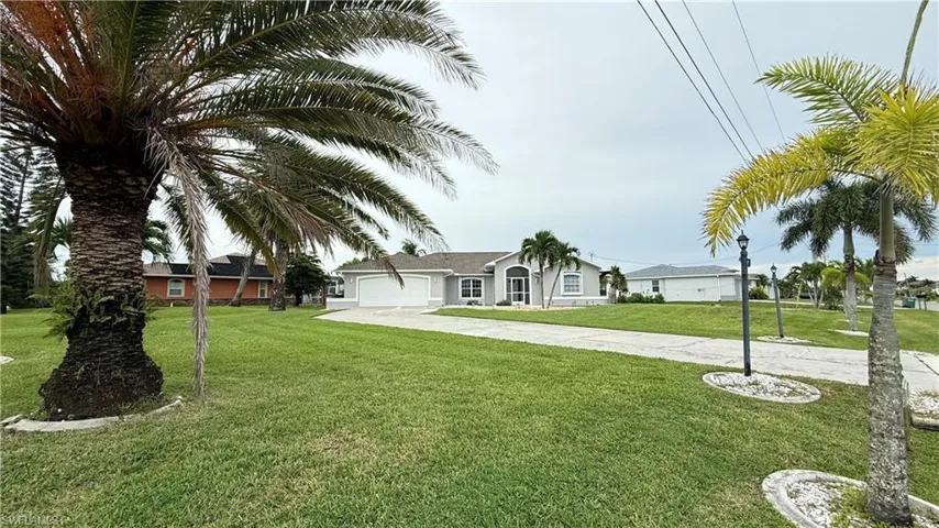 Single story home featuring driveway, an attached garage, and a front yard