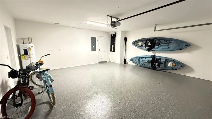 Garage featuring water heater, heating unit, and electric panel