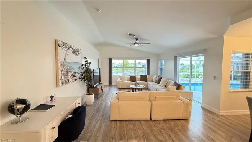 Living area with light wood-style floors, an office area, ceiling fan, and vaulted ceiling