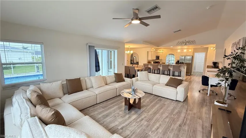 Living area with a ceiling fan, light wood-style flooring, lofted ceiling, and suspended lighting