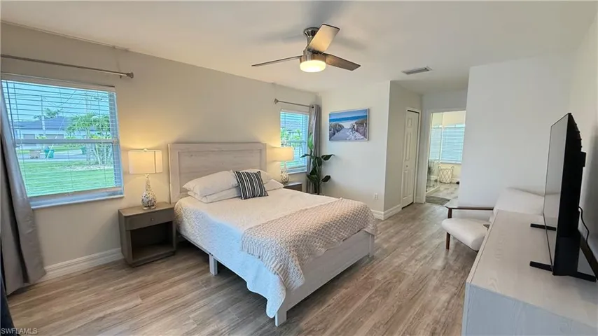 Bedroom with a closet, light wood finished floors, a ceiling fan, and ensuite bathroom