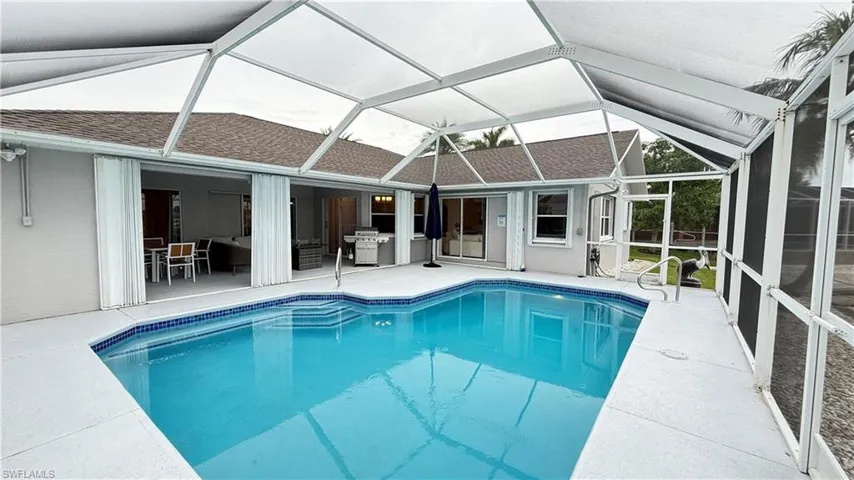 Swimming pool featuring a patio, a sunroom, area for grilling, and glass enclosure