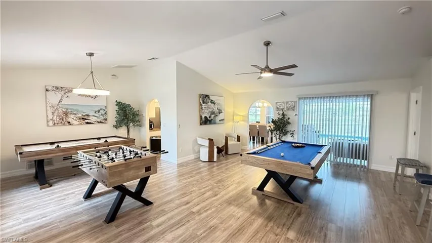 Game room featuring billiards table, vaulted ceiling, arched walkways, wood finished floors, and a ceiling fan