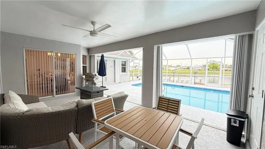 View of patio featuring an outdoor pool, glass enclosure, a ceiling fan, a sunroom, and outdoor dining space