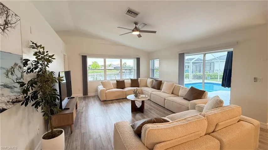 Living area with ceiling fan, wood finished floors, and vaulted ceiling