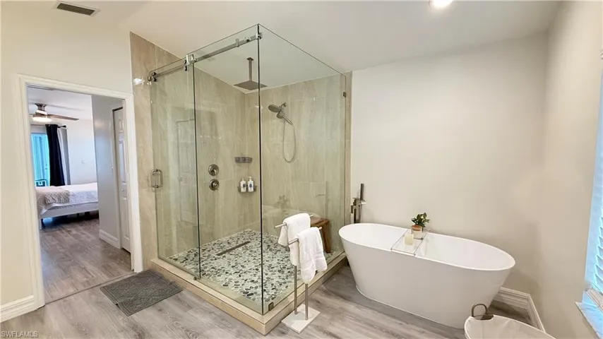 Ensuite bathroom with a stall shower, wood finished floors, and a freestanding tub