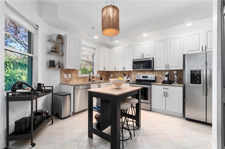 The kitchen boasts custom shelving, a new center island, new faucet, custom blinds, and lighting fixture, and stainless appliances.