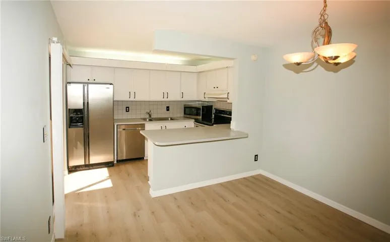 Kitchen featuring white cabinetry, stainless steel appliances, a light-toned countertop, and a tiled backsplash
