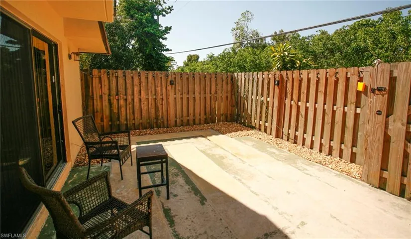 Private patio area featuring a concrete surface, surrounding privacy fencing, and a perimeter of decorative gravel