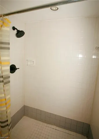 Tiled shower enclosure featuring a matte black rainfall showerhead and coordinating fixtures