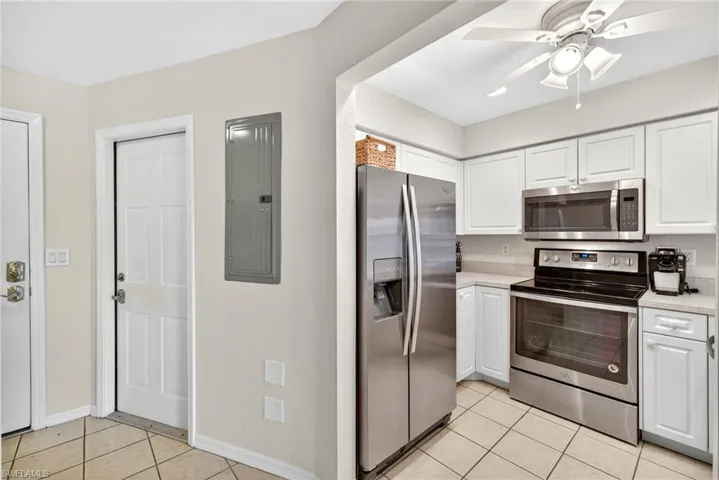 Kitchen featuring stainless steel appliances, light tile patterned floors, electric panel, and white cabinets