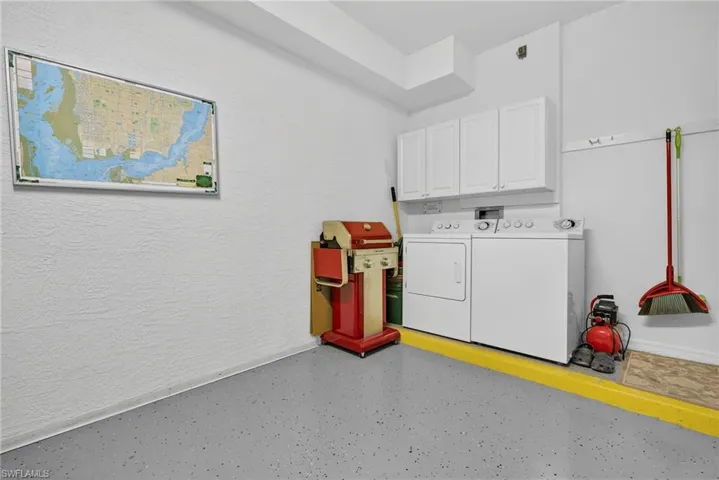 Laundry area featuring a textured wall, washer and clothes dryer, and cabinet space