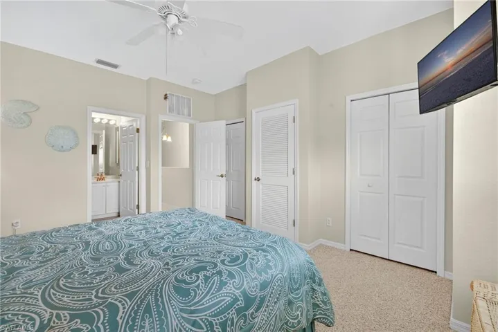 Bedroom with carpet floors, multiple closets, ceiling fan, and connected bathroom