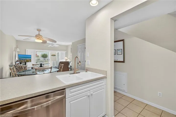 Kitchen with stainless steel dishwasher, light tile patterned floors, open floor plan, a ceiling fan, and white cabinets