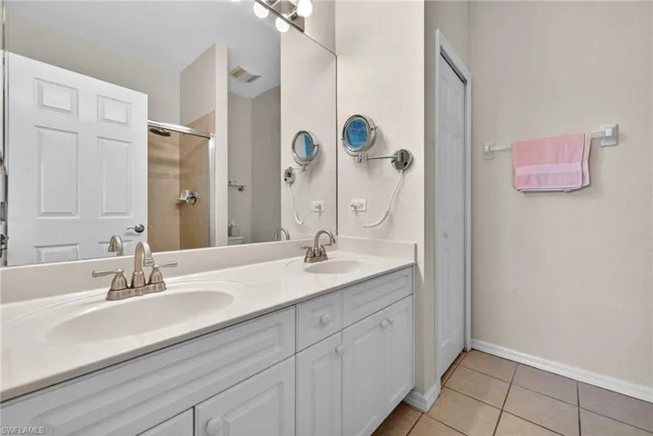 Full bathroom with light tile patterned floors, double vanity, a closet, and tiled shower