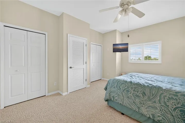 Carpeted bedroom with two closets and ceiling fan