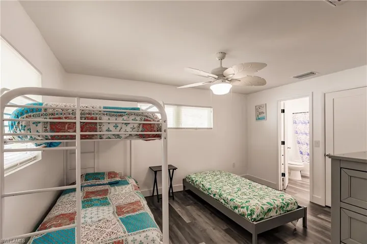 Bedroom with dark wood finished floors, ceiling fan, and connected bathroom