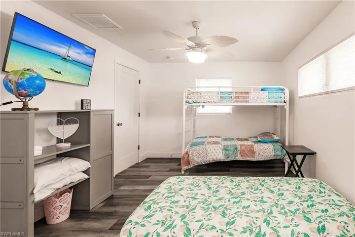 Bedroom with dark wood-type flooring, a ceiling fan, and multiple windows