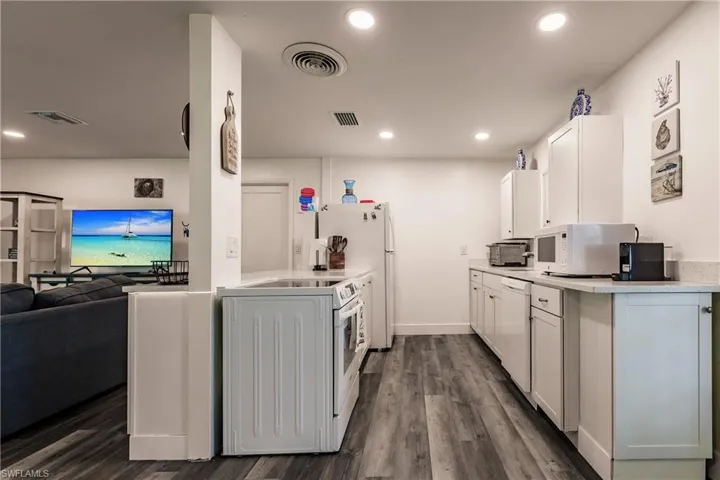 Kitchen with white cabinetry, dark wood finished floors, white appliances, washer / clothes dryer, and open floor plan