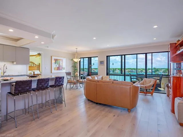 Living room with ornamental molding, light wood-style floors, and recessed lighting