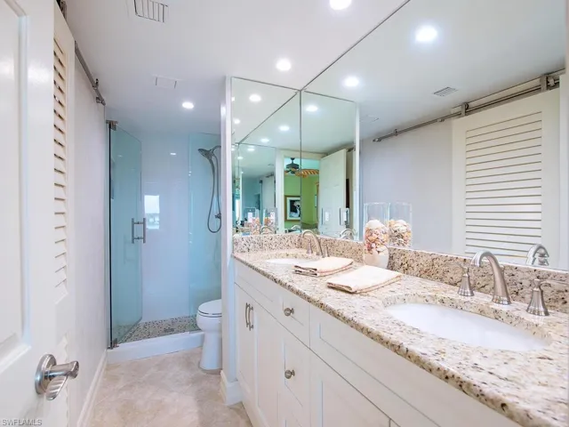 Bathroom with double vanity, a stall shower, recessed lighting, light tile patterned floors, and a closet