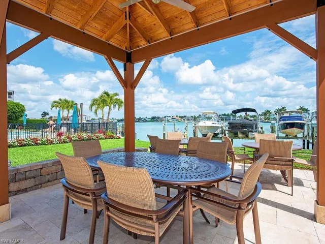 Gazebo with wet bar and grills and a water view, outdoor dining space, and a ceiling fan
