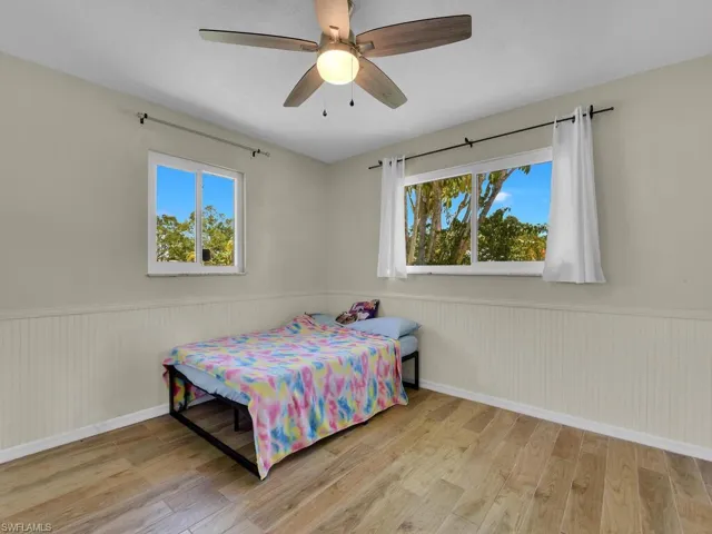Bedroom with ceiling fan, multiple windows, and light hardwood / wood-style flooring