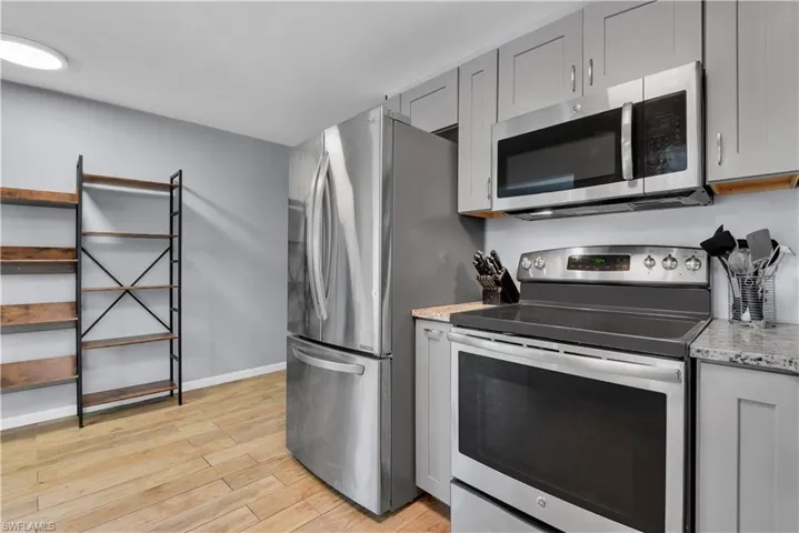 Kitchen featuring light hardwood / wood-style floors, light stone countertops, gray cabinetry, and stainless steel appliances