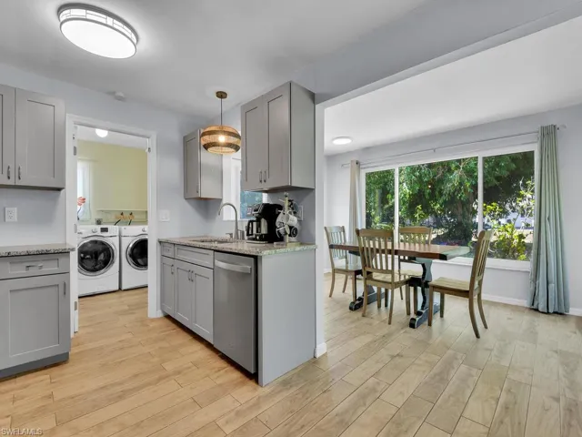 Kitchen with hanging light fixtures, light wood-type flooring, washer and clothes dryer, gray cabinets, and dishwasher