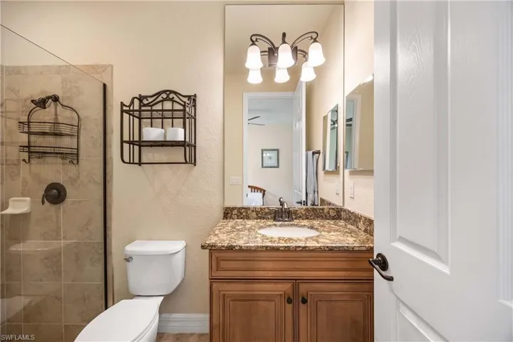 Full bathroom # 3with an inviting chandelier, toilet, vanity, and a tile shower