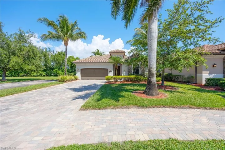 Mediterranean / spanish-style house with a tile roof, stucco siding, a front lawn, decorative driveway, and a garage