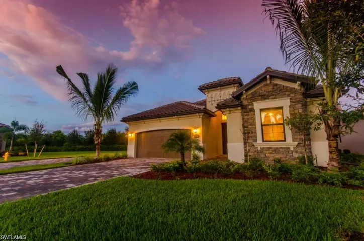 Mediterranean / spanish-style house with an attached garage, a yard, driveway, and stone siding