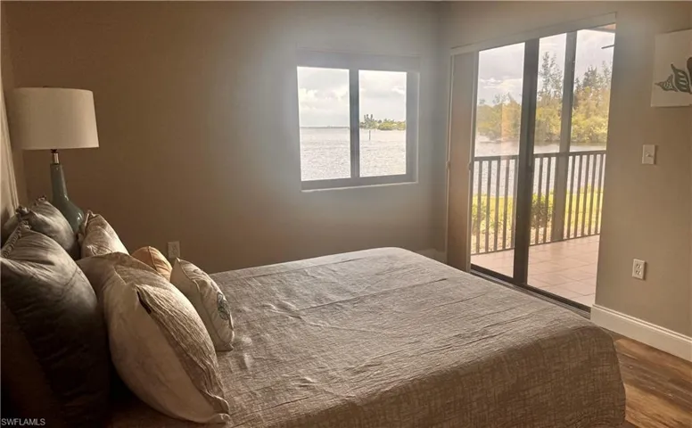 Bedroom featuring access to outside, a water view, and wood finished floors