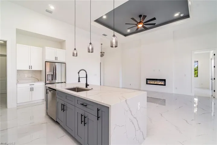 Kitchen with white cabinetry, tray ceiling, stainless steel appliances, and quartz counters